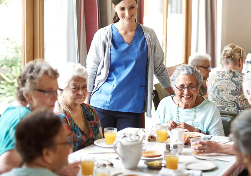 Aged care residents sharing a meal with a carer
