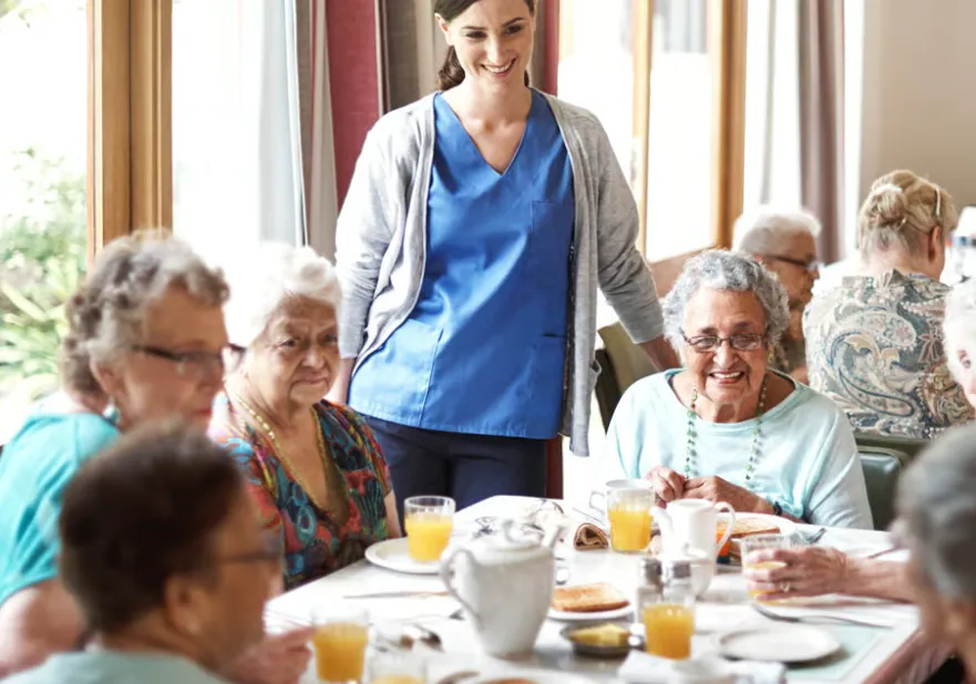 Aged care residents sharing a meal with a carer
